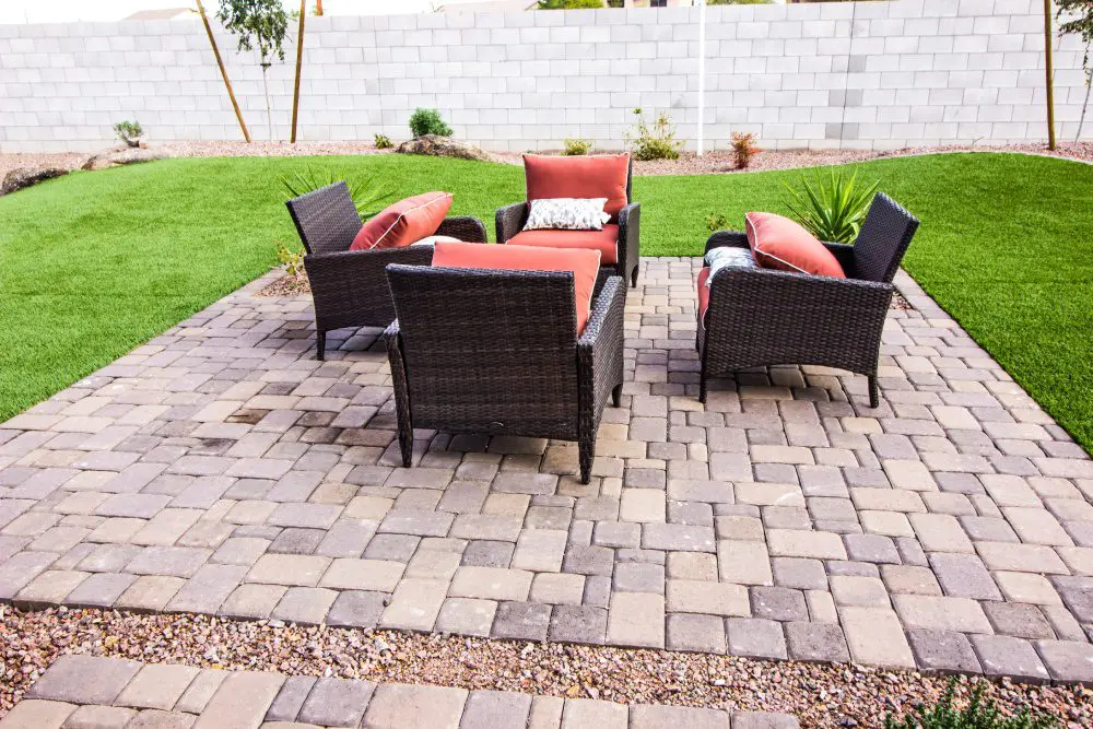 Outdoor patio set with orange cushions on a brick patio.