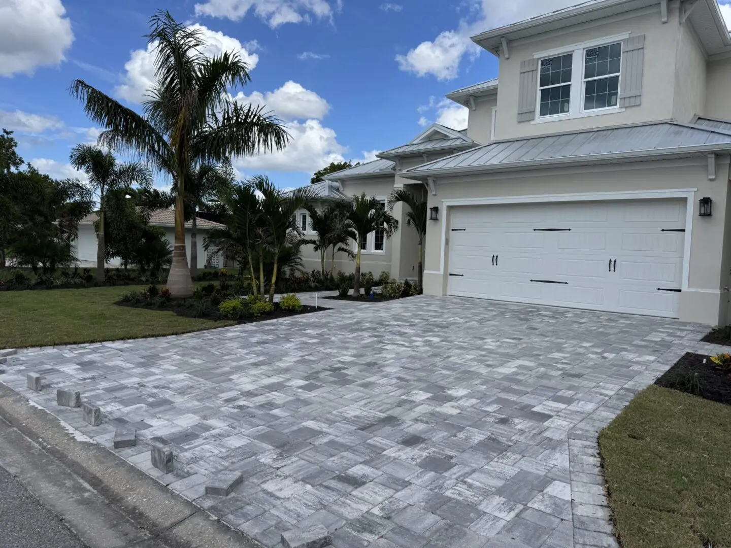 Modern home with a clean, patterned driveway and tropical landscaping.