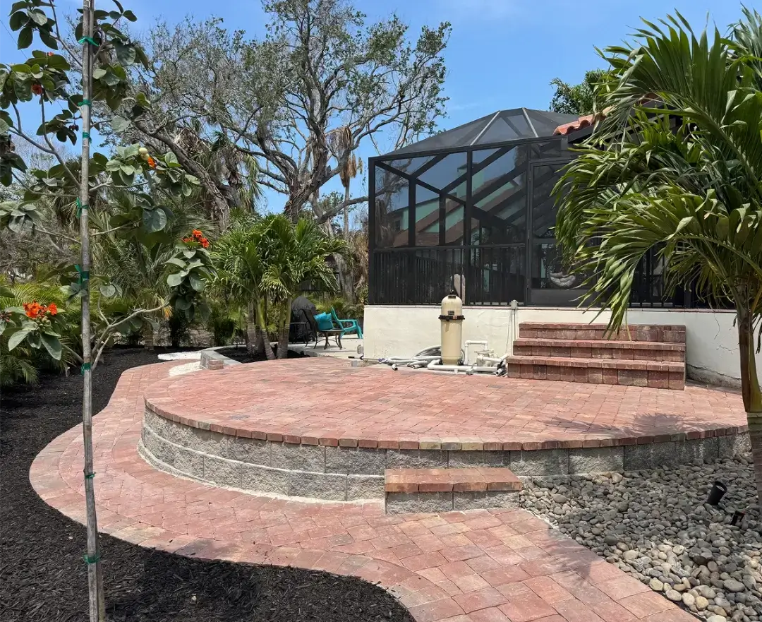 Outdoor patio area with curved brick steps and a screened enclosure.